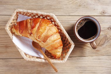 Taze pişmiş kruvasan ve kahveler ahşap masada, üst tarafta.