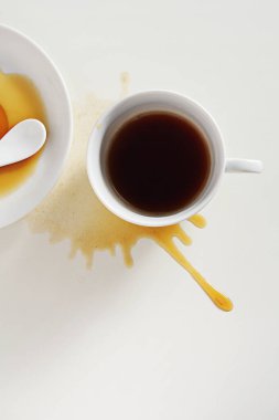 Beyaz masaya dökülmüş bir fincan kahve, üst manzara.