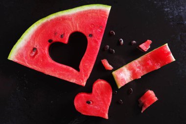Black Metal arka planda kalp şeklinde kesilmiş bir karpuz dilimi.