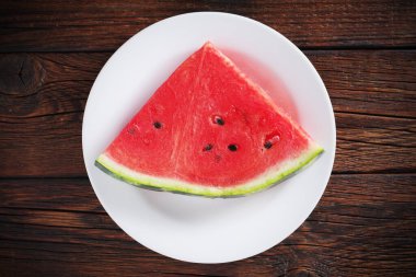 Ahşap zemin üzerinde bir tabakta karpuz dilimi, üst manzara.