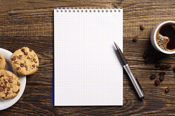 Notepad and coffee with cookies