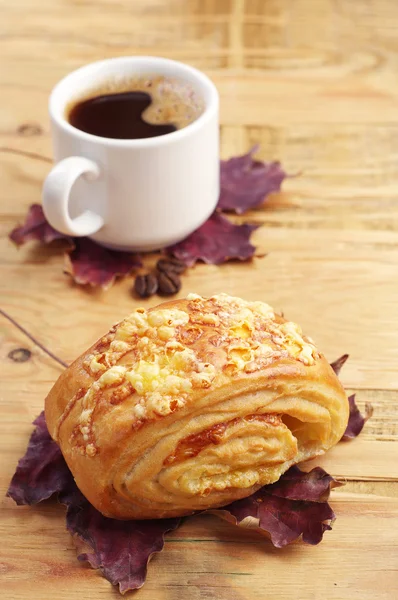 Bun, coffee and autumn leaves — Stock Photo, Image