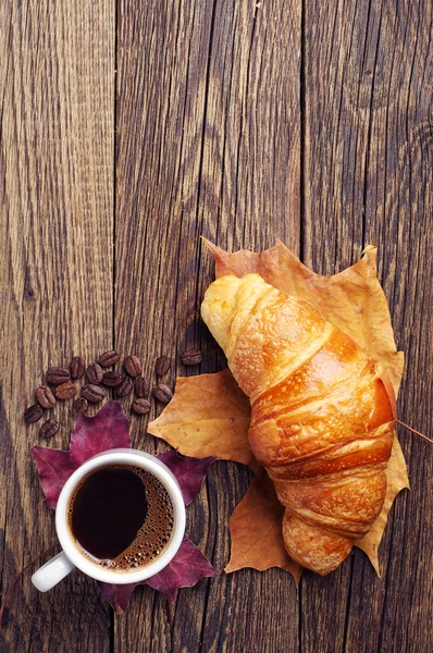 Kahvi, croissant ja syksyn lehdet — kuvapankkivalokuva