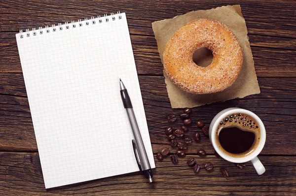 Anteckningsbok och kopp kaffe med donut — Stockfoto