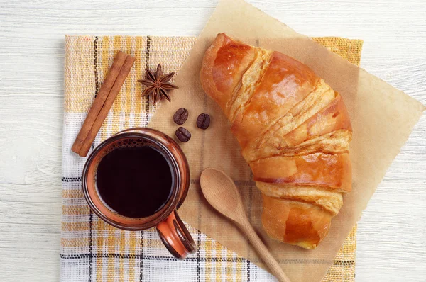 Cup of hot coffee and tasty croissant — Stock Photo, Image