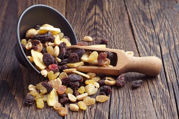 Zwarte kom met noten en rozijnen — Stockfoto