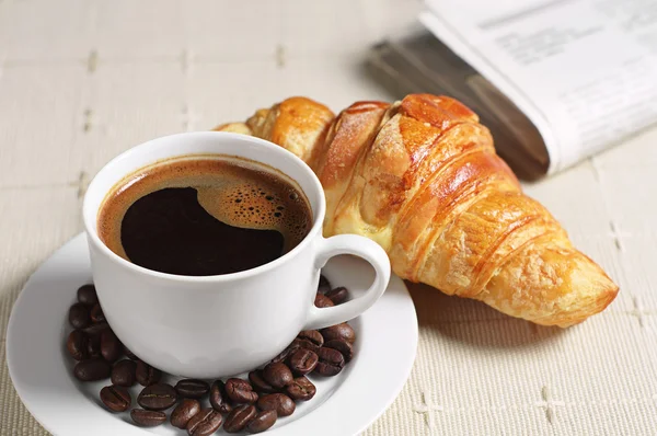 Croissant al caffè e giornale — Foto Stock