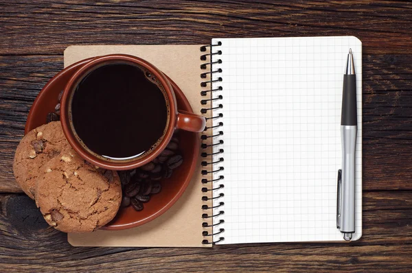 Kladblok en bruin kopje koffie — Stockfoto