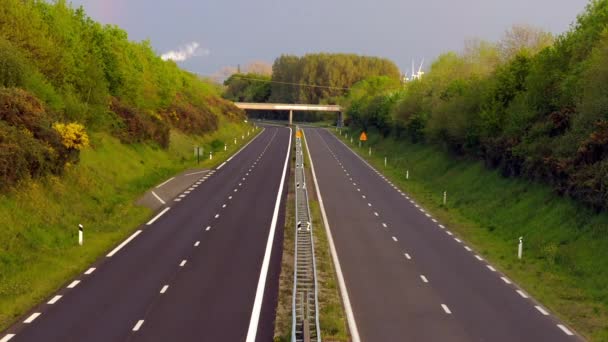 Timelapse - Zoomare su una corsia autostradale diritta con veicoli al crepuscolo dal giorno alla notte - un fumo, turbine eoliche e un arcobaleno sullo sfondo . — Video Stock