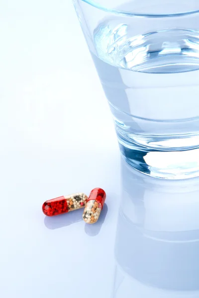 Verre d'eau et capsules de médecine — Photo