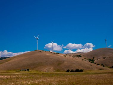 Rüzgar türbinleriyle alternatif enerji. Forca Caruso Abruzzo 'da mavi gökyüzü ile harika bir gün. Dağları aşan büyük rüzgar türbinleri..