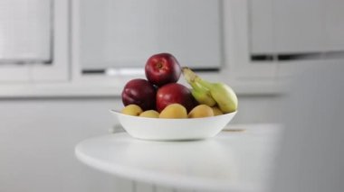 Adam kırmızı şeftali masanın üzerine alır.