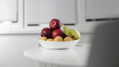 Adam kırmızı şeftali masanın üzerine alır.