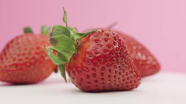 Rijpe aardbeien draaien tegen een roze achtergrond — Stockvideo