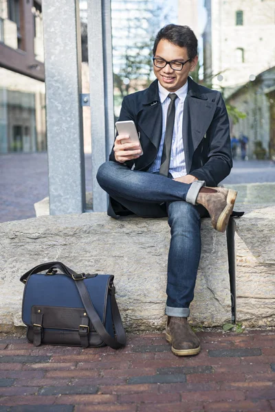 Jonge Aziatische man kijken naar mobiele telefoon — Stockfoto