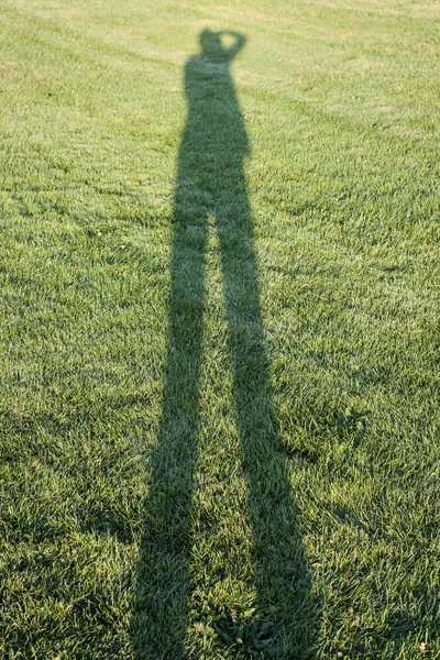 Persona proyectando sombra sobre hierba — Foto de Stock