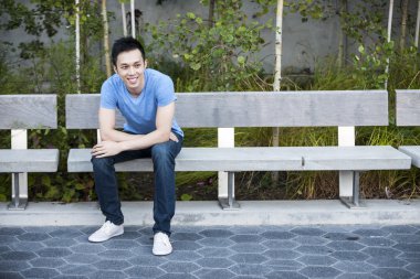 Mutlu genç Asyalı adam bankta