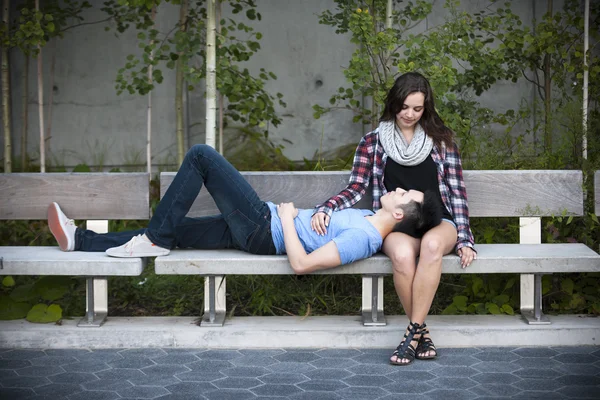 Jeune couple sur banc de parc — Photo