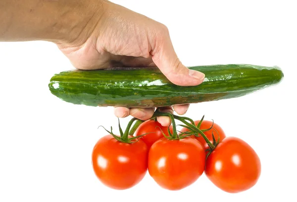 Persona sosteniendo un pepino y un montón de tomates — Foto de Stock