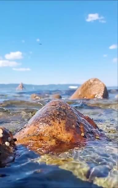 背景に認識できない人とゆっくりとした動きで海岸で波が砕ける ノルウェーの夏の部分的に曇った空の下で撮影されたフィールドと低角度の浅い深さ — ストック動画