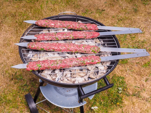 Shish kebab prepared over a black round shaped charcoal barbecue — Stock Photo, Image