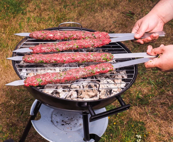 Un chef poniendo shish kebab de carne roja en una barbacoa de carbón — Foto de Stock