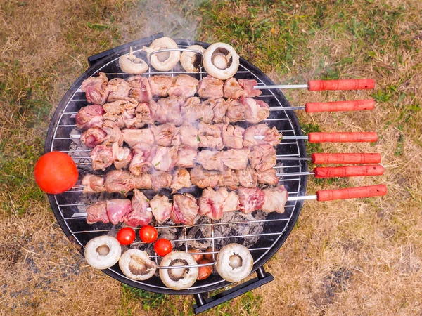 Shish kebab prepared over a black round shaped charcoal barbecue — Stock Photo, Image