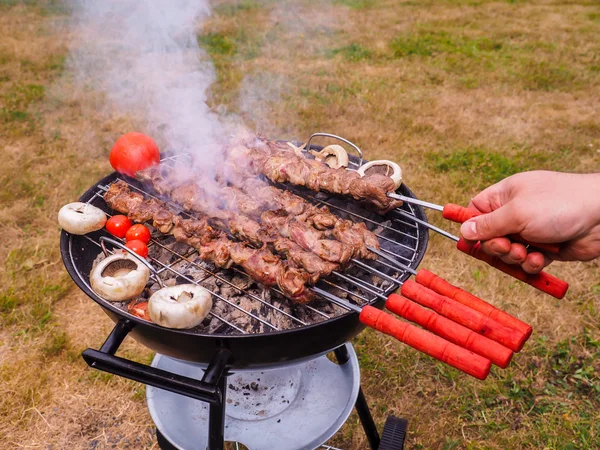 Primo piano di uno chef che gira spiedini di carne sul barbecue caldo — Foto Stock