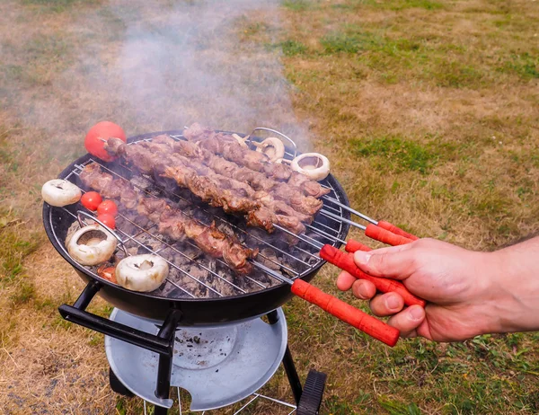 Nahaufnahme eines Kochs, der Fleischspieße auf heißem Grill dreht — Stockfoto