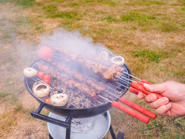 Primo piano di uno chef che gira spiedini di carne sul barbecue caldo — Foto Stock