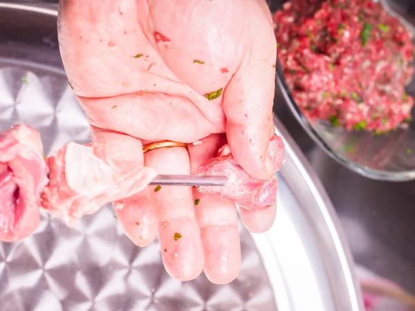Крупный план шеф-повара, который заносит куски мяса на шампур и делает — стоковое фото