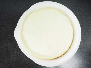 Hamur siyah masada beyaz bir plastik kapta kanıtlanmış