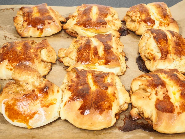 Frisch gebackene Zimtbrötchen auf Backpapier geflochten — Stockfoto