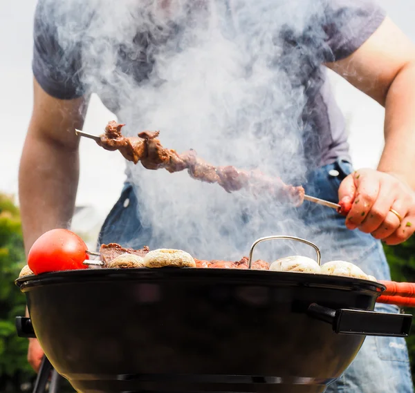 Chef covered in smoke grilling skewers — Stock Photo, Image