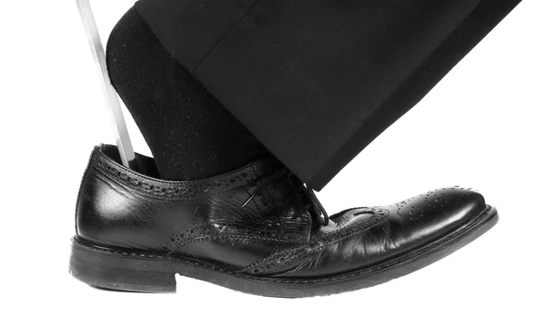 Person wearing black suit and socks entering foot into black leather shoes with shoehorn — Stock Photo, Image