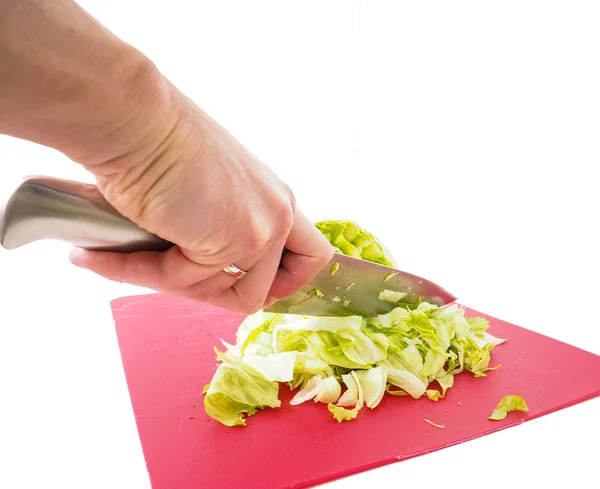 Hand cutting fresh green lettuce salad with grey metal knife on — Stock Photo, Image