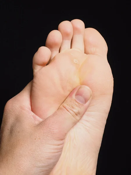 Pressure point massage under foot with thumb isolated towards bl Royalty Free Stock Photos