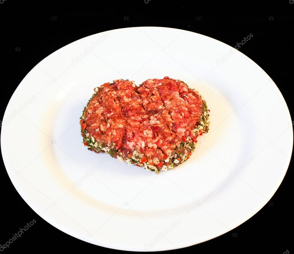 Seasoned raw red hamburger on white plate
