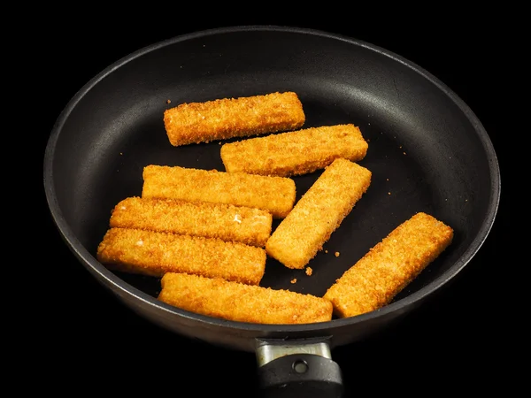 Crumbed fish fingers in fry pan Royalty Free Stock Images