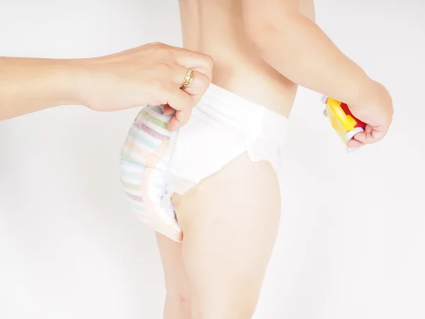 Mother dressing up toddler in diaper while standing, holding a y — Stock Photo, Image