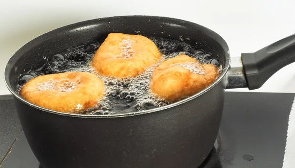 Donuts cooking in boiling oil — Stock Photo, Image