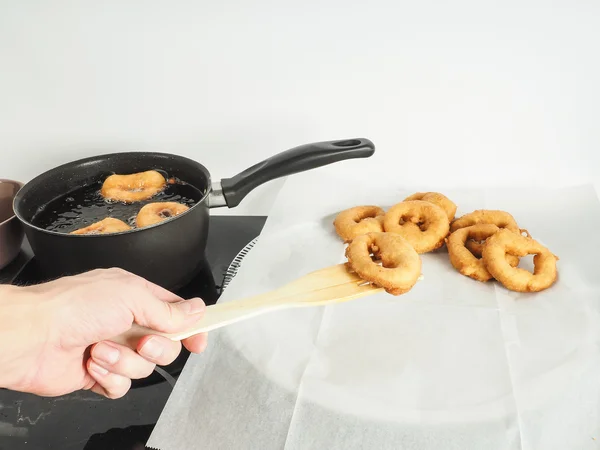 Hand of person lifting freshly made donut from bolier to paper — Stock Photo, Image