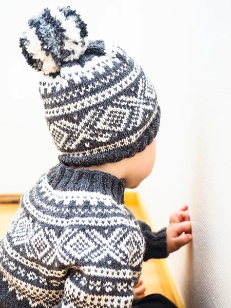 Маленький ребенок в трикотажной одежде, шляпе и ругательстве — стоковое фото