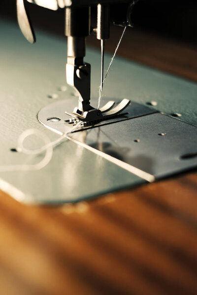 Крупный план швейной машины с освещённой рабочей зоной