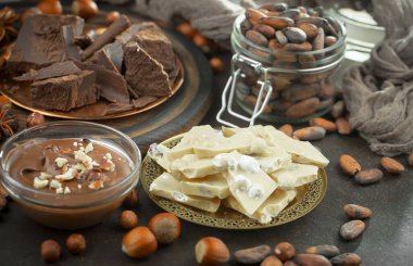 Eskimiş bir arka planda kakao çekirdeği ve fındıklı siyah çikolata..