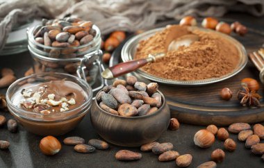 Eskimiş bir arka planda kakao çekirdeği ve fındıklı siyah çikolata..