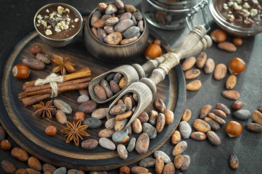 Eskimiş bir arka planda kakao çekirdeği ve fındıklı siyah çikolata..