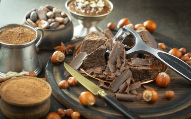 Eskimiş bir arka planda kakao çekirdeği ve fındıklı siyah çikolata..