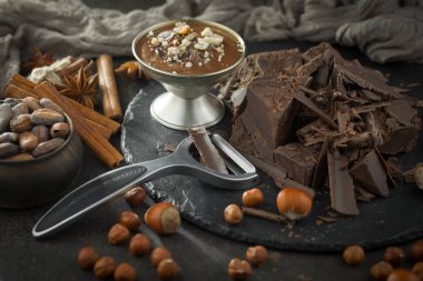Eskimiş bir arka planda kakao çekirdeği ve fındıklı siyah çikolata..