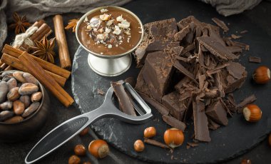 Eskimiş bir arka planda kakao çekirdeği ve fındıklı siyah çikolata..